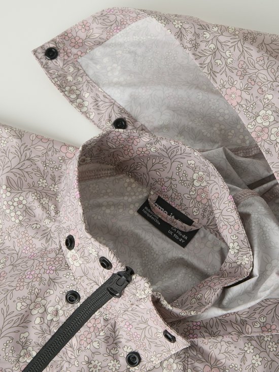 Detail van roze regenjas met bloemenprint, rits en knopen.