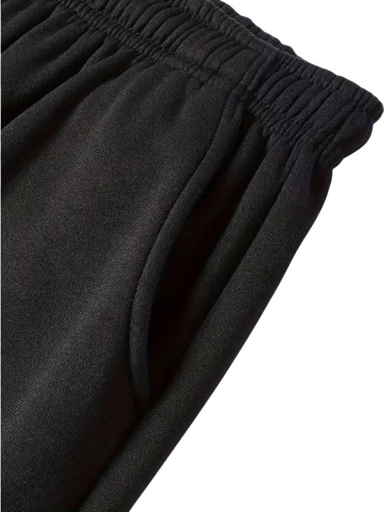 Close-up van de tailleband en zak van een zwarte joggingbroek.