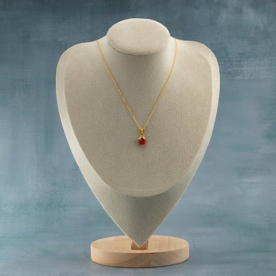Gouden ketting met oranje steen op een mannequin.