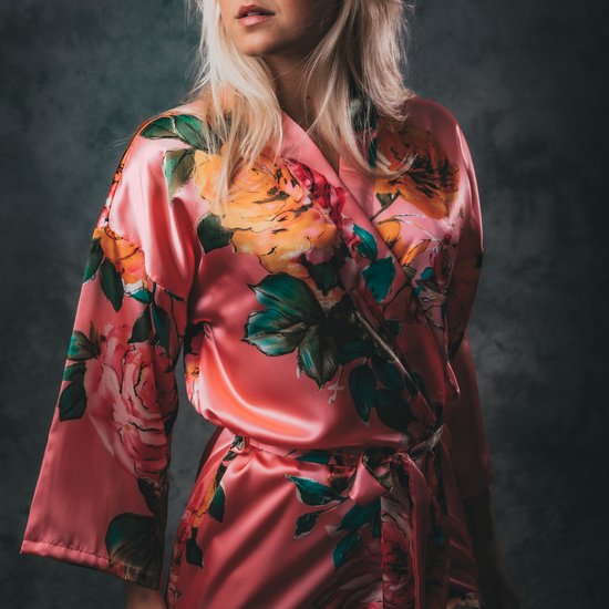 Koraalrode satijnen kimono met bloemenprint, model met blonde haren, gedragen over een ceintuur.