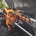 Lamsrack roostert op een spit boven brandende infraroodbrander van barbecue.