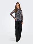 Model draagt een nauwsluitend shirt met coltrui, abstract dierlijk patroon in blauw en beige, met wijde zwarte broek.