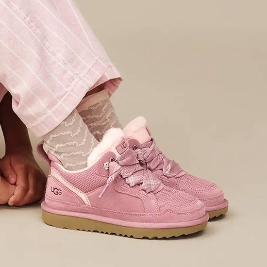 Roze UGG sneakers met faux fur, gedragen door een kind met gestreepte sokken.
