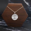 Zilverkleurige levensboom ketting met zon, maan en sterren op een houten display.