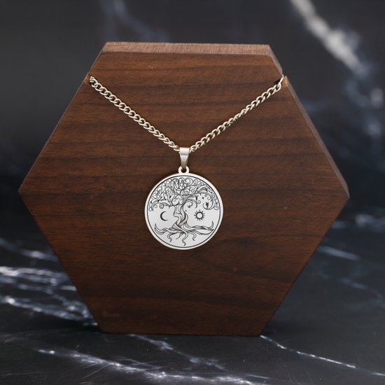 Zilverkleurige levensboom ketting met zon, maan en sterren op een houten display.
