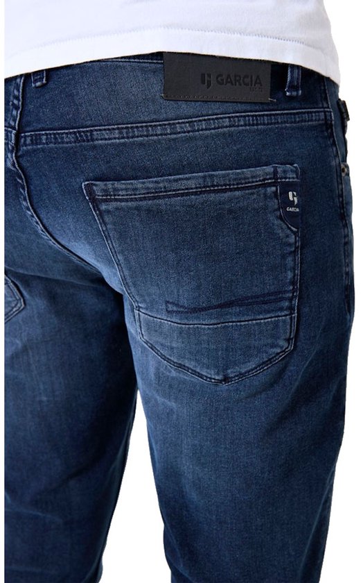 Close-up van de achterzakken van een donkerblauwe jeans met Garcia logo.