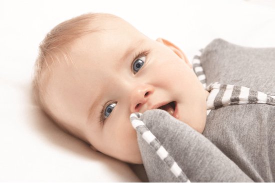 Close-up van een baby met blauwe ogen die in een grijze Love to Dream™ Swaddle Up™ ligt.