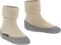 Twee beige huissokken met omgeslagen zachte rand en grijze antislipzool. Een label met 'FALKE' is zichtbaar op de zijkant van de rechtersok.