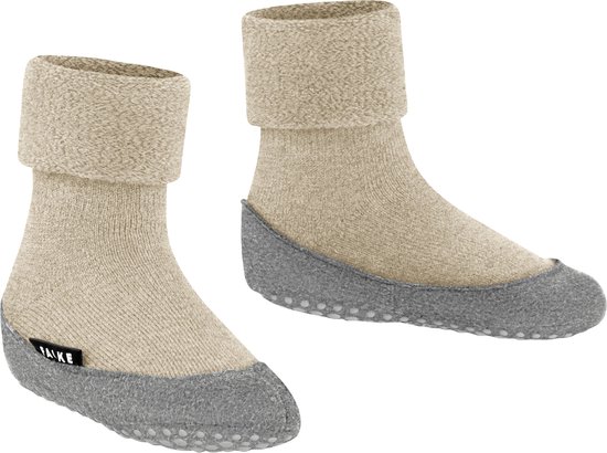 Twee beige huissokken met omgeslagen zachte rand en grijze antislipzool. Een label met 'FALKE' is zichtbaar op de zijkant van de rechtersok.