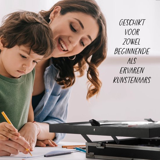 Een lachende moeder kijkt toe hoe haar zoon met potlood tekent, met een kunstkoffer op de voorgrond.