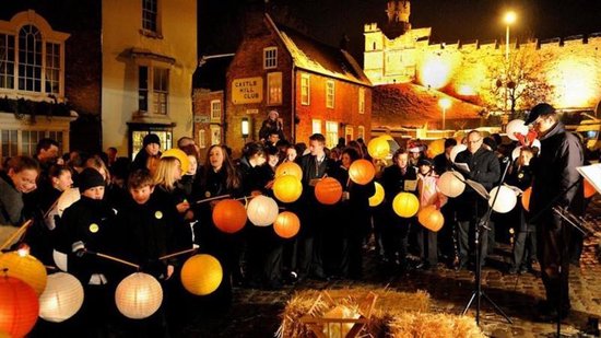 Mensen met lampionnen bij een kasteel 's avonds, een baby in een kribbe op de voorgrond.