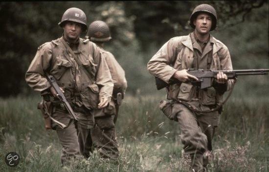 Twee soldaten in gevechtstenue, gewapend, lopen door grasland. Een soldaat draagt een geweer.