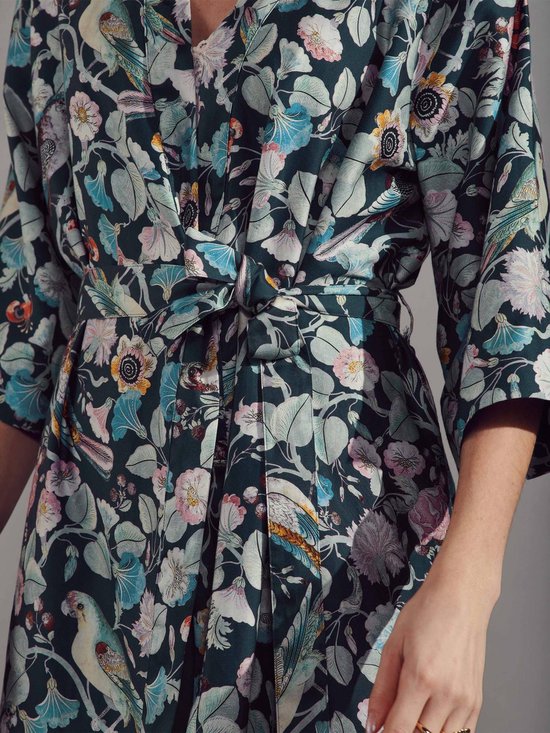 Detail van een donkergroene kimono met bloemen- en vogelprint, ceintuur geknoopt.
