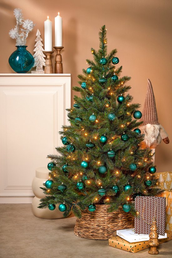Kerstboom versierd met jadekleurige kerstballen en lampjes, met een kerstman-achtige figuur ernaast.