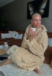 Beige badjas met capuchon van zacht fleece, vrouw houdt mok vast.