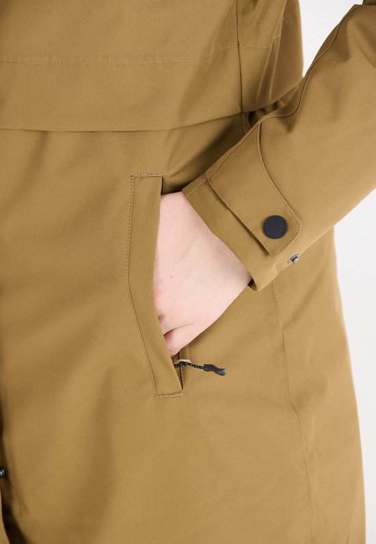 Detail van een hand in de zak van een bruine parka. De zak sluit met een rits met een zwart lusje.