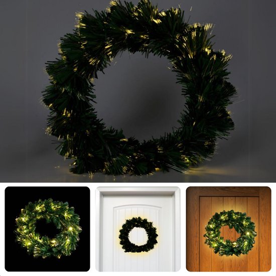 Kerstkrans met donkergroene takjes en warm witte fiber optic verlichting. Getoond op een zwarte achtergrond, witte deur en houten deur.