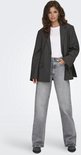 Model in een grijze jeans met wijde pijpen en een oversized gestreepte blazer.