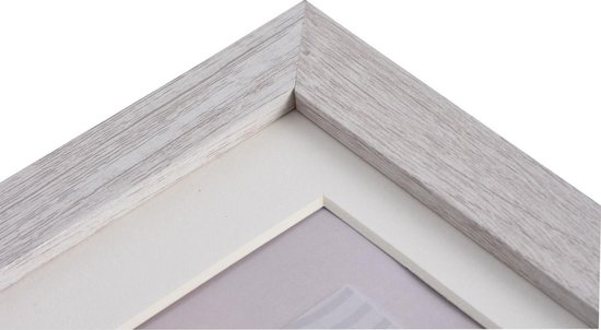Close-up van de hoek van een lichte houten fotolijst met een crème passe-partout en een subtiele afbeelding.