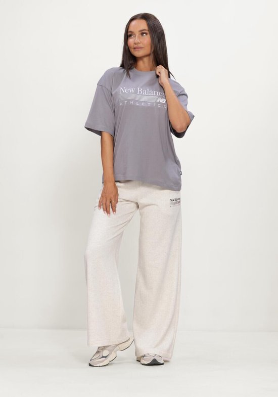 Model in een grijze New Balance Athletics oversized T-shirt met logo, gecombineerd met een lichtgrijze joggingbroek.