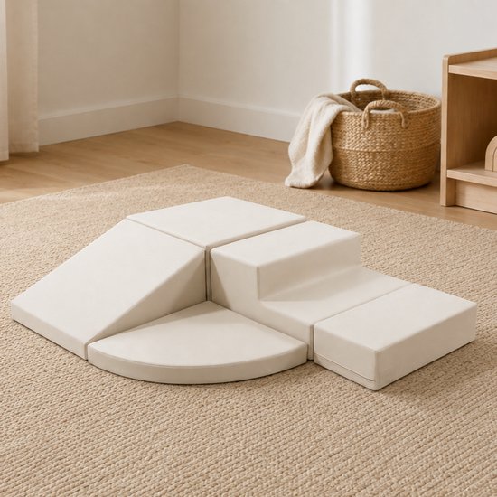Grijze, zachte speelblokken in verschillende vormen, waaronder een helling, kwartronde en een trap, op een beige tapijt.