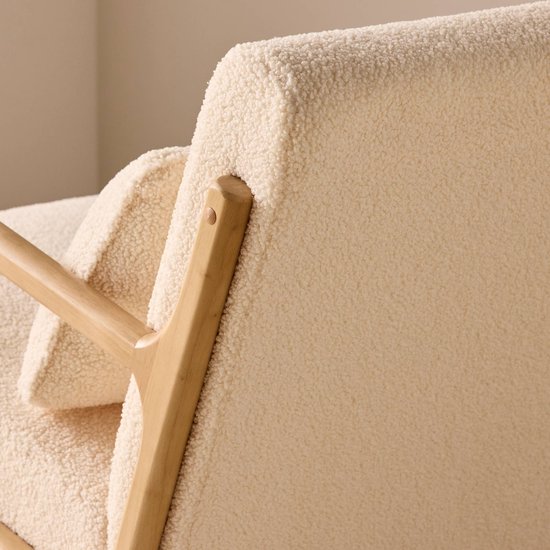 Detail van de achterkant van een schommelstoel met crèmekleurige bouclé bekleding en een licht houten frame.