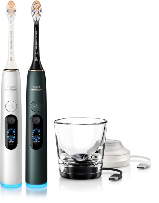 Twee Philips Sonicare DiamondClean 9000 elektrische tandenborstels in zilverwit en middernachtgroen, met laadglas en USB-kabel.