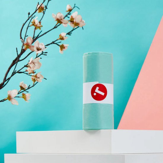 Rol lichtblauwe composteerbare afvalzakken met een wit label en rood logo, naast een tak met roze bloesems.