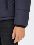 Detail van de mouw van een donkerblauwe jongensjas, met gebreide boord.