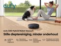 Een vrouw doet yoga met een hond, naast een zwarte eufy G50 robotstofzuiger op een mat.