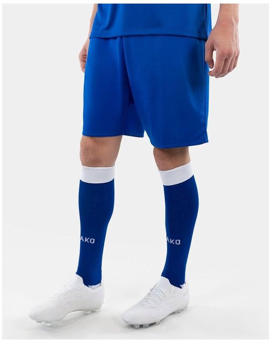 Un homme porte un short de sport bleu et des chaussettes assorties à bords blancs. Chaussures de football blanches.