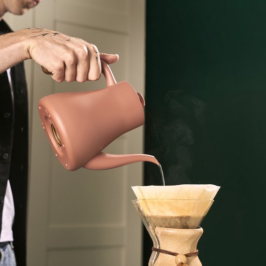 Roze waterkoker met slanke tuit, water wordt boven een koffiefilter gegoten.
