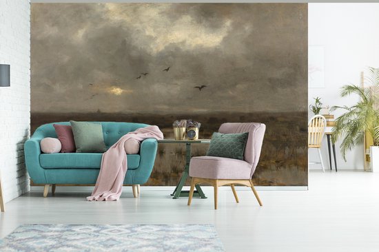 Un coin salon avec un canapé bleu-vert et un fauteuil rose, face à un tableau de marais au coucher du soleil.