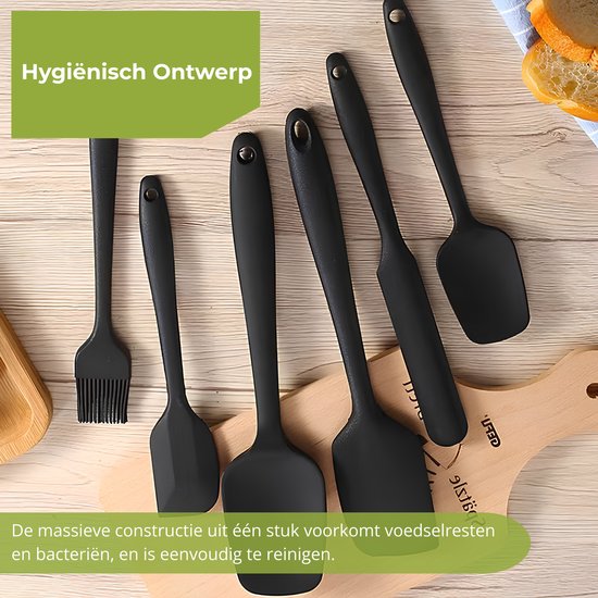 Diverse zwarte siliconen spatels en een bakkwast liggen op een houten tafel.