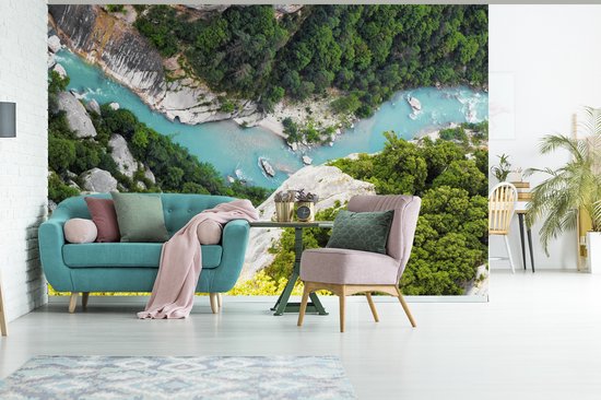 Rivière bleu clair serpentant dans une gorge avec des arbres verts et des rochers, sur une tapisserie au-dessus d'un canapé.