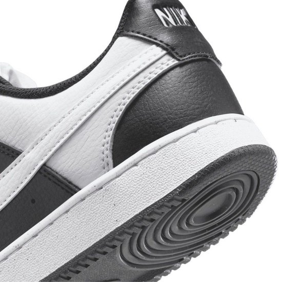 Detail van de hak van een zwarte en witte Nike sneaker. Zwarte 'NIKE' letters op de hak.