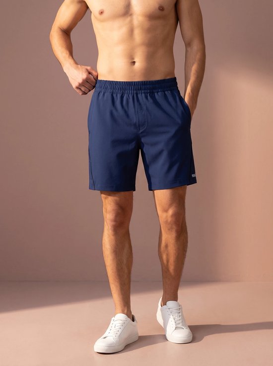 Man met donkerblauwe sportshort en witte sneakers, vooraanzicht.