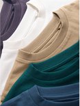 Close-up van de kragen van vijf gestapelde T-shirts in donkergrijs, wit, beige, groen en blauw.
