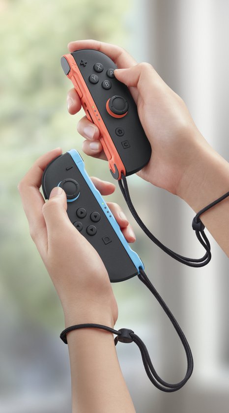 Twee handen houden neonrode en blauwe Joy-Con controllers met polsbandjes vast.