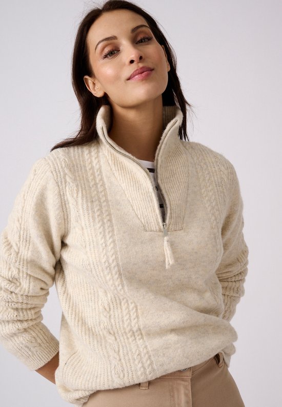 Vrouw met gebreide beige trui met kabelpatroon en halve rits.