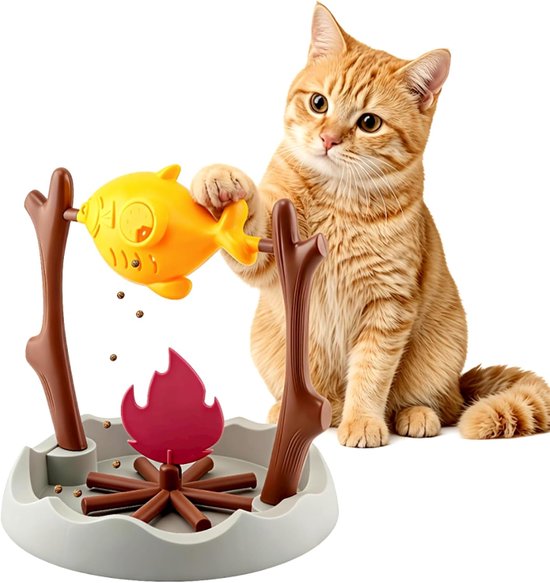 Oranje kat zit naast een gele visvormige voerdispenser boven een kampvuur met brokjes.