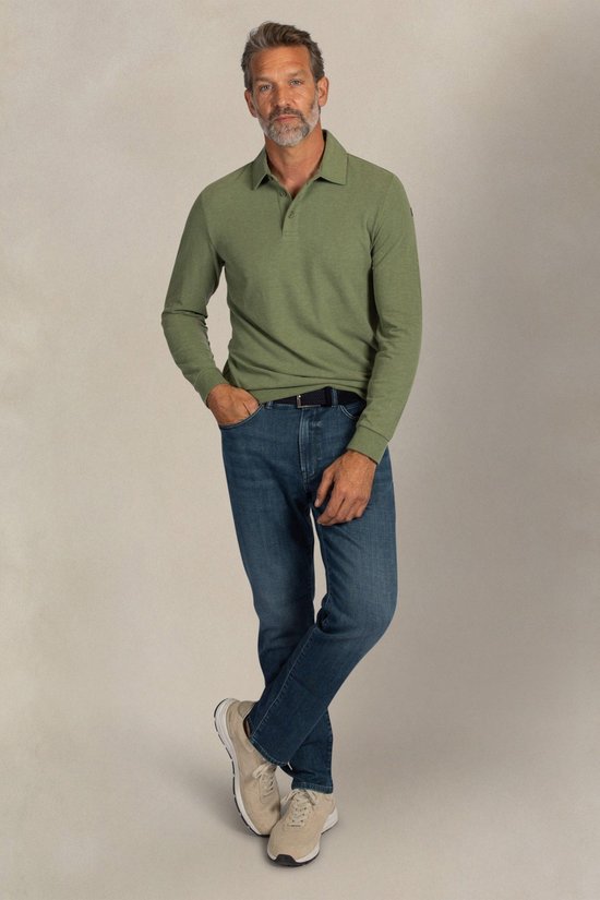 Man met grijzend haar, die een lichtgroen poloshirt met lange mouwen en donkerblauwe jeans draagt.