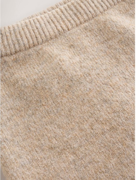 Close-up van de tailleband en stof van een beige gebreide babybroek.