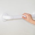 Een hand wordt gebruikt om een witte wandbeugel met geribbelde grip vast te pakken.