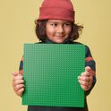 Jongen met rode muts houdt een groene LEGO bouwplaat met 10x10 noppen vast.