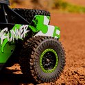 Close-up van de achterkant van een groene en witte RC-auto "Acid Runner" op stoffig terrein.