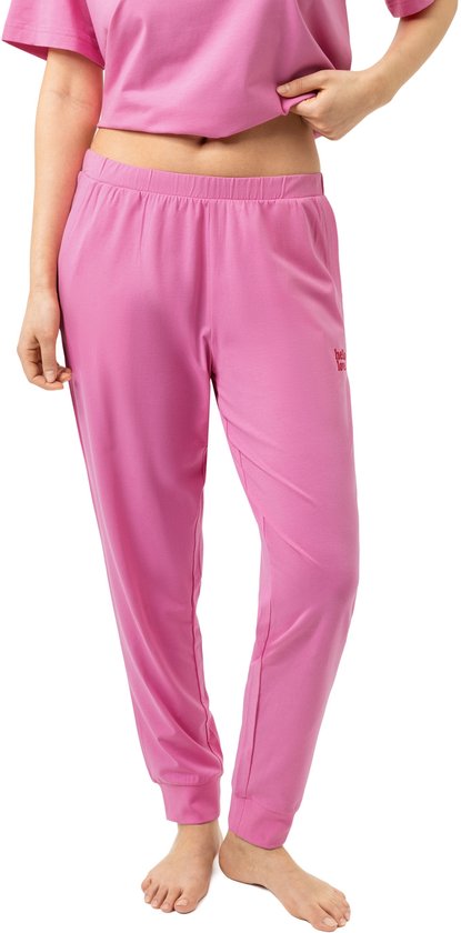 Model draagt roze pyjamabroek met rode tekst 'hello love' op de heup.