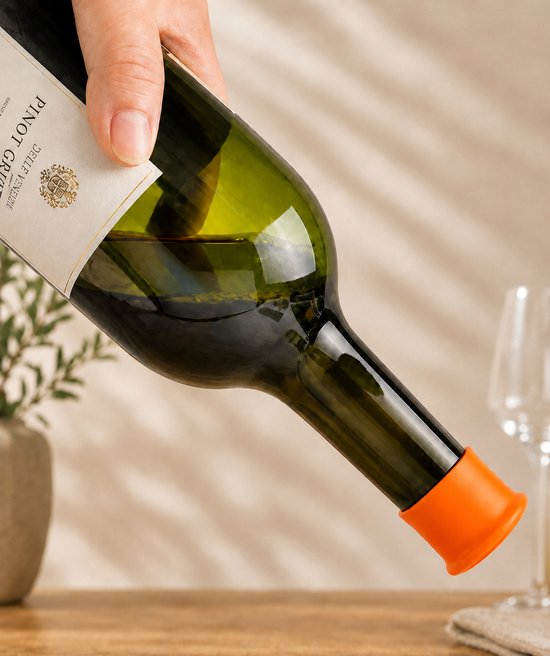 Een hand giet wijn uit een groene fles met een oranje dopje op de tuit.