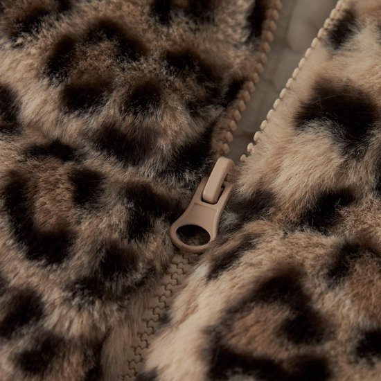 Detailopname van de beige ritssluiting van een bruine teddy jas met luipaardprint.