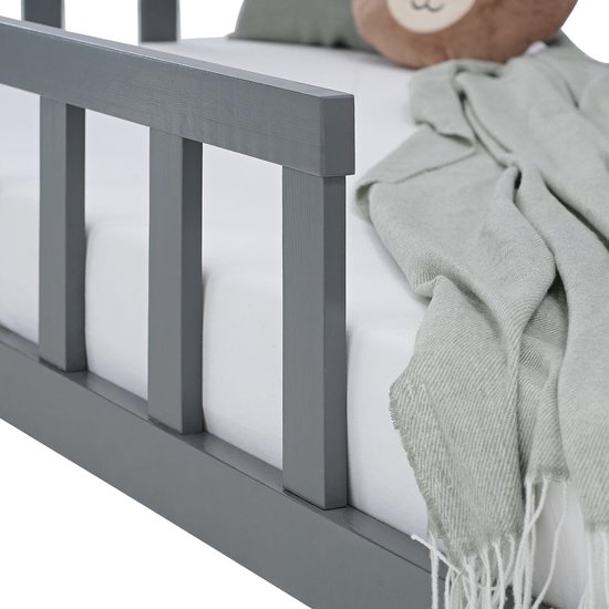 Detailopname van de grijze houten spijlen en een zachte deken op het peuterbed.